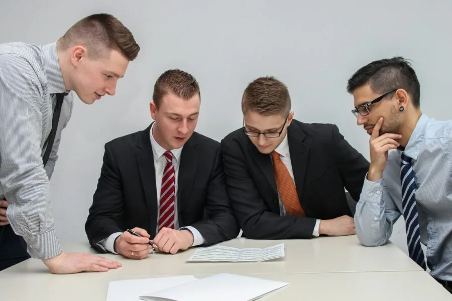 four men looking to the paper on table
