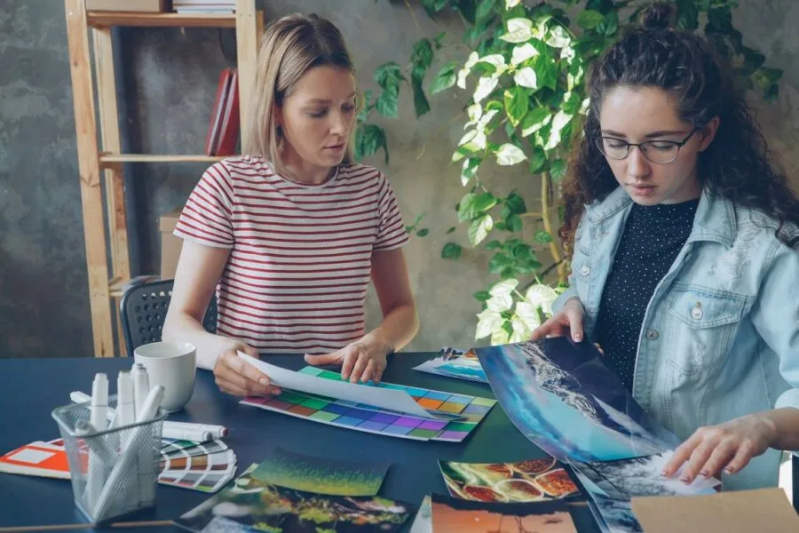 Two women are working together on artwork.