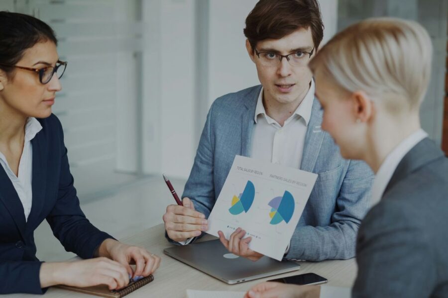 Three professionals discussing charts in a meeting.