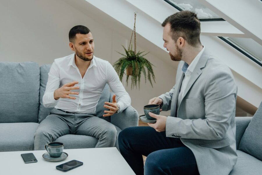 two men sitting on a couch talking to each other
